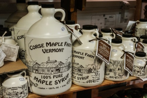 Bottles of Corse Maple Farm 100% pure maple syrup displayed on a wooden shelf.