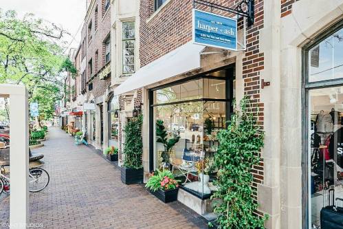 A charming street view featuring the storefront of "harper + ash" with greenery and colorful planters.