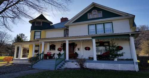 A charming two-story house decorated for the holidays, featuring wreaths and a Santa figure on the porch.