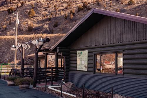 A rustic log cabin building with signage, surrounded by a mountainous landscape.