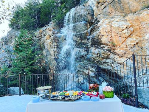 A beautiful outdoor setting with a waterfall and a table filled with colorful food and desserts.