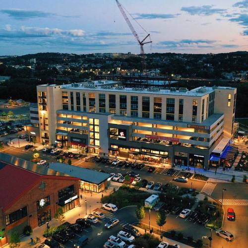 Aerial view of a modern building complex at dusk, with cars parked and a construction crane in the background.