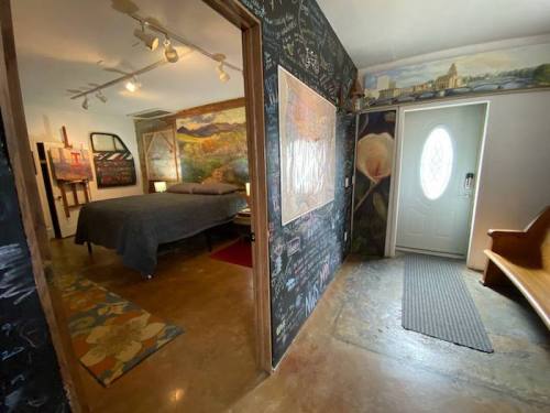 A cozy room with a bed, chalkboard walls, and a welcoming entrance featuring a door and a wooden bench.
