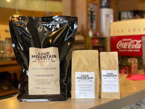 A bag of Loud Mountain Trading Co. coffee beans alongside two smaller bags, all labeled with flavor profiles.