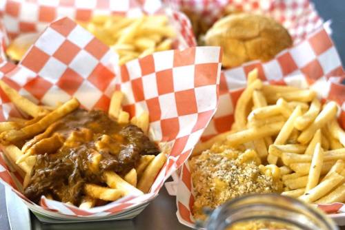 A variety of food in checkered baskets, including fries topped with gravy, a burger, and macaroni and cheese.