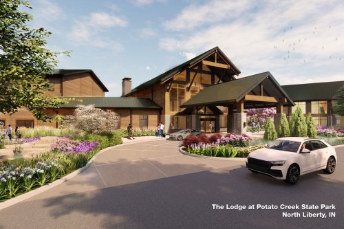 A modern lodge entrance surrounded by lush greenery and colorful flowers at Potato Creek State Park, North Liberty, IN.
