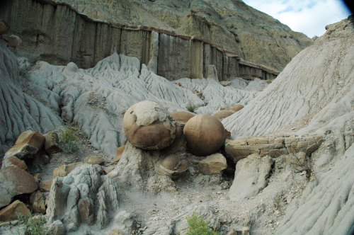 A rocky landscape featuring unique, rounded stone formations amidst textured, eroded earth.