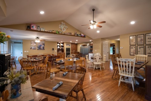 Cozy dining area with wooden tables and chairs, warm lighting, and a welcoming atmosphere.