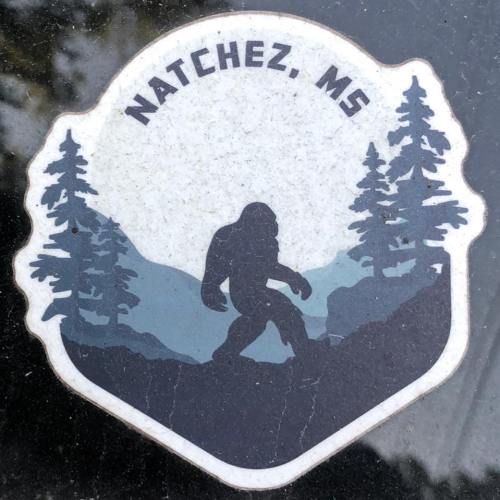 A sticker featuring a silhouette of Bigfoot among trees and mountains, labeled "Natchez, MS."