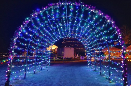 A colorful archway adorned with vibrant lights, creating a festive atmosphere at night.