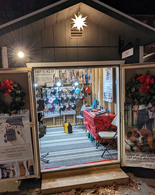 A cozy shop with a red table, displaying cell phone accessories, decorated for the holidays with wreaths and lights.