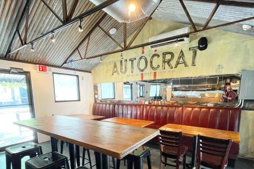 Interior of a restaurant named "AUTOCRAT," featuring wooden tables, red booths, and a rustic metal roof.