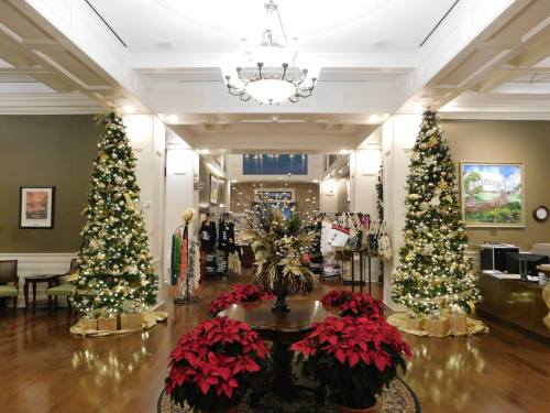 A festive lobby decorated with Christmas trees, poinsettias, and holiday lights, creating a warm, inviting atmosphere.