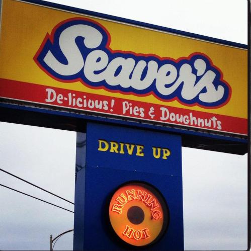 Sign for Seaver's featuring "Delicious! Pies & Doughnuts" with a "Running Hot" neon indicator and a drive-up option.