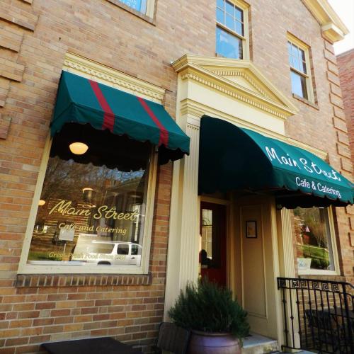 Exterior of Main Street Cafe & Catering, featuring green awnings and a brick facade.