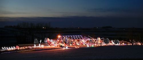 A festive house decorated with colorful lights and holiday displays, set against a twilight sky.