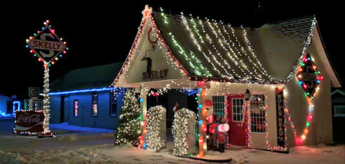 A cozy building decorated with colorful Christmas lights, featuring a vintage gas pump and a festive sign.