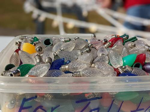 A clear container filled with colorful, vintage-style Christmas light bulbs in various shapes and colors.