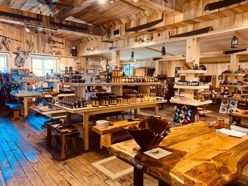 A rustic store interior with wooden shelves displaying various products, including jars and crafts, in a cozy atmosphere.
