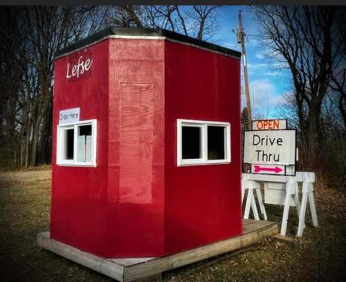 A small red drive-thru booth with a sign that says "Lefse" and "Open" next to a window for ordering.