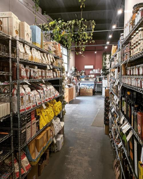 A grocery store aisle lined with shelves of various packaged foods and products, leading to a checkout area.