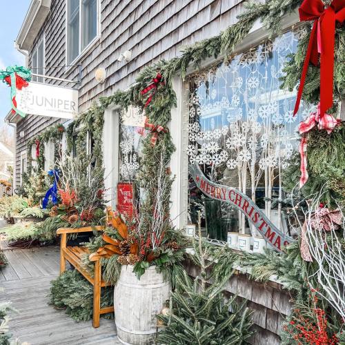 A festive storefront decorated with greenery, ribbons, and a "Merry Christmas" sign, creating a cheerful holiday atmosphere.