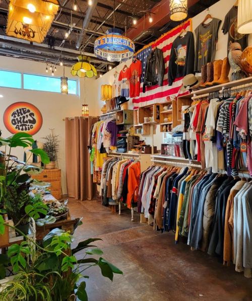 A cozy vintage shop interior with colorful clothing racks, decorative lights, and a warm, inviting atmosphere.