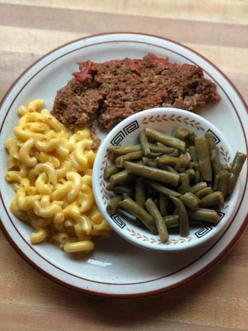 A plate with meatloaf, macaroni and cheese, and a side of green beans.