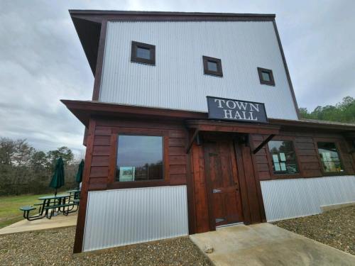 A rustic town hall building with a wooden facade and metal siding, featuring a sign that reads "TOWN HALL."