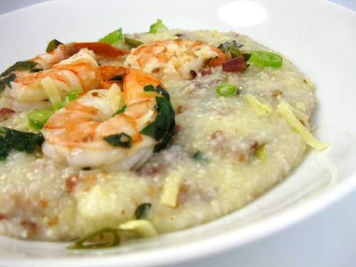 A bowl of creamy grits topped with sautéed shrimp and green onions.