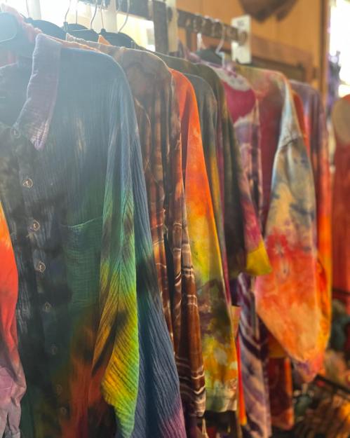 A row of colorful, tie-dyed shirts hanging on a rack, showcasing vibrant patterns and textures.