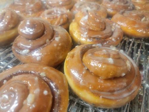 Close-up of freshly baked cinnamon rolls with a glossy glaze, arranged on a cooling rack.