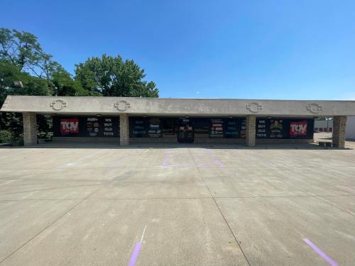 Storefront with signs reading "We Buy Old Toys" and "We Sell Old Toys," set against a clear blue sky.