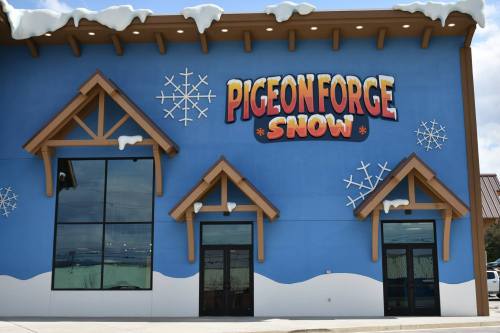 Bright blue building with "Pigeon Forge Snow" sign and snowflake decorations, featuring large glass doors.