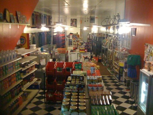 A colorful grocery store interior with shelves stocked with various products and a checkered floor.