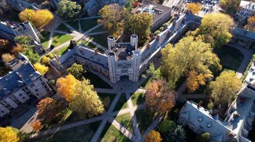 Aerial view of a historic university campus with autumn trees and pathways intersecting around a central building.