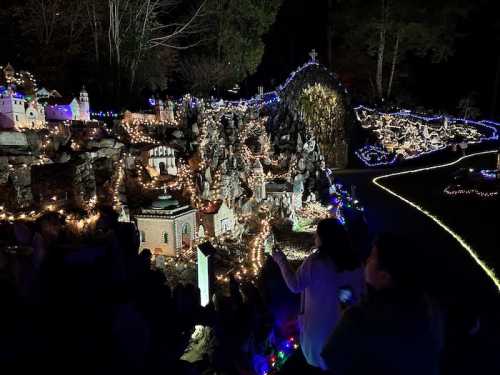 A beautifully lit miniature village scene at night, with colorful lights and intricate details among rocks and trees.