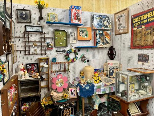 A vibrant display of vintage items, including antiques, collectibles, and decorative pieces on a pegboard wall.