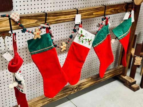 A display of colorful Christmas stockings hanging on a wooden rack, decorated with festive embellishments.