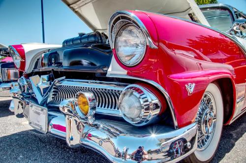 Close-up of a vintage red car with chrome details and a shiny front grille, showcasing classic automotive design.