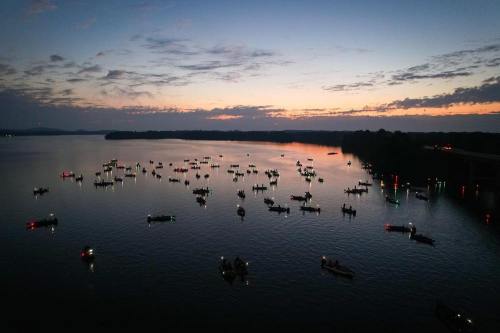 A serene twilight scene over a lake filled with numerous boats, their lights reflecting on the water.