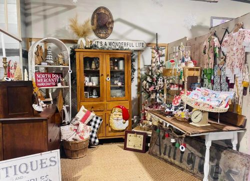A cozy holiday-themed shop display with vintage decor, handmade items, and a festive tree.