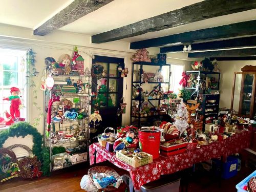A cozy room filled with holiday decorations, vintage items, and a table covered in festive crafts and ornaments.