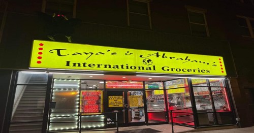Brightly lit storefront of "Tanya's & Abraham's International Groceries," featuring colorful signage and open entrance.