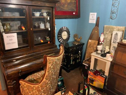 A vintage furniture display featuring a desk, cabinet, and various decorative items, with sale signs for discounts.