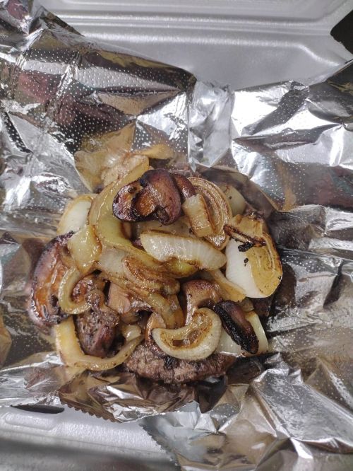A juicy burger topped with sautéed onions and mushrooms, wrapped in foil.