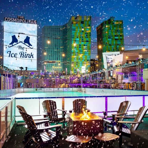 A winter scene at The Ice Rink with a fire pit, surrounded by colorful buildings and falling snowflakes.