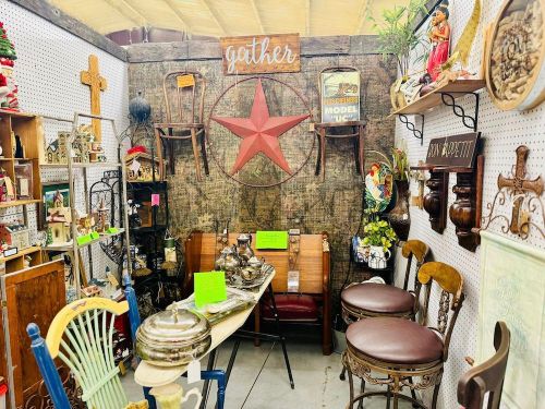 A cozy antique shop display featuring vintage furniture, decor, and a large red star on a wooden wall.