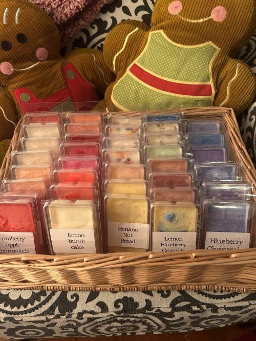 A woven basket filled with various scented wax melts, labeled with flavors like lemon bundt cake and blueberry cheesecake.