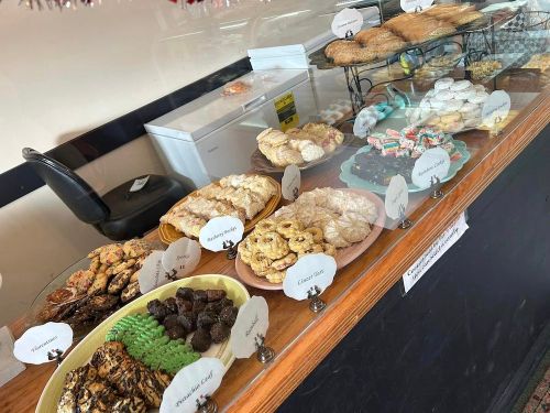A display case filled with various baked goods, including cookies, pastries, and colorful treats.